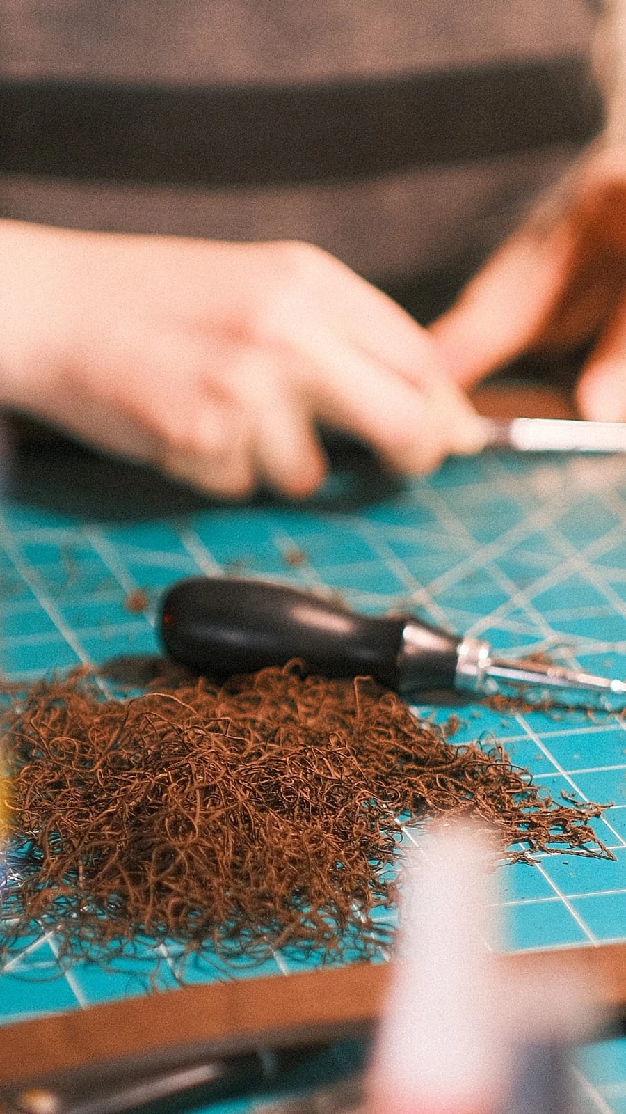 Fine leather shavings and an edge tool on the bench