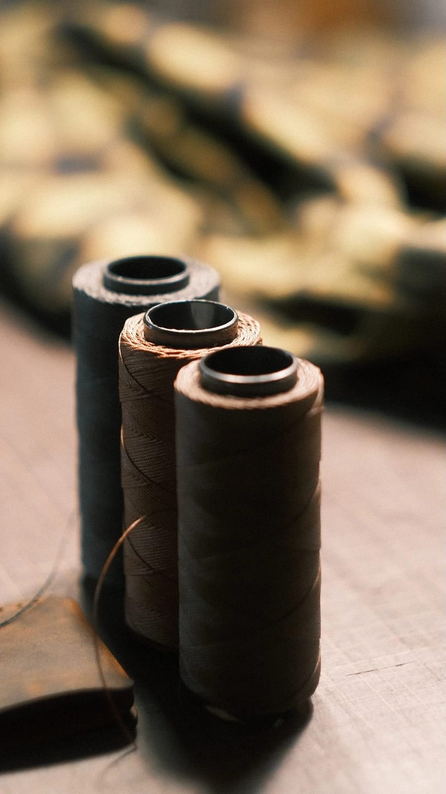 Three spools of thread in brown and grey tones on a table