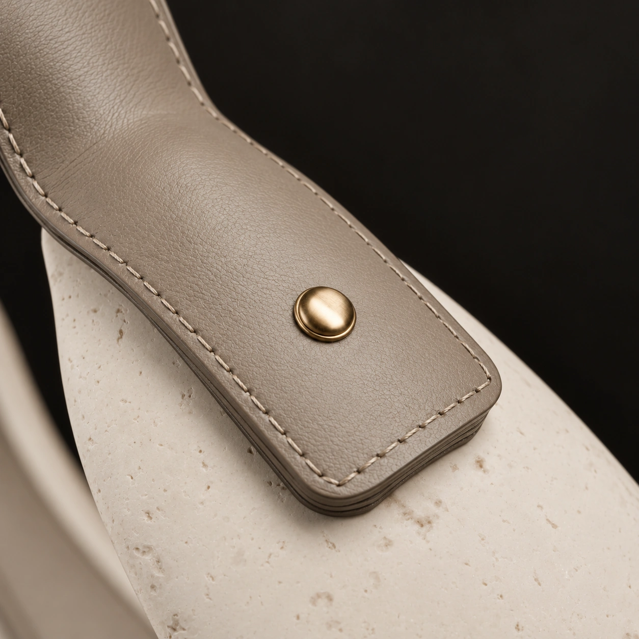 The champagne brass rivet and leather layers against the ivory shell